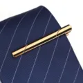 Vue détaillée d'une pince à cravate dorée avec surface polie pour un look professionnel. - Champagne