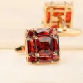 Gros plan de detail sur les superbes boutons de manchette carres dores avec pierres rouges. - Or Brillant Cristal Rouge