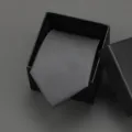 Detailed close-up of a stylish black striped necktie neatly displayed inside a black gift box. - 8cm Grey Matte Plain Zipper With Gift Box