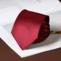 Classic dark red business necktie rolled up nicely on a decorative book background. - Smooth Hand-Tied Style / 8cm / Burgundy
