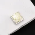 Gros plan de manchette carrée en nacre avec motif à carreaux sur poignet de chemise blanche. - Coquillage Blanc Carré
