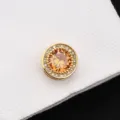 Détail en gros plan d'un bouton de manchette rond doré avec cristal ambre et strass. - Cristal Doré Prospère