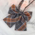 Detailed close-up view of grey and orange plaid JK bow tie for school uniform shirts. - Dark Gray Orange Plaid