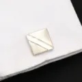 Gros plan détaillé de boutons de manchette géométriques argentés sur chemise blanche. - Simple et Élégant