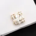 Gros plan détaillé d'un bouton de manchette en cristal carré sur un tissu blanc texturé. - Or Brillant Cristal Blanc