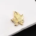 Gros plan détaillé du bouton de manchette en forme de feuille dorée à la texture raffinée. - Feuille d'érable Dorée