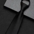 Gedetailleerd overzicht van de zwarte ritsdas met gladde textuur en nette voorgeknoopte knoop. - 8cm Zwart Glanzend Rits Stijl