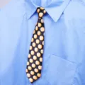 Primo piano della cravatta nera con simpatiche stampe di mele gialle abbinata a una camicia. - Stampa Mela Stile Donna