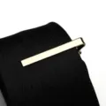 Gold tie clip detail shot showcasing elegant metallic shine on classic patterned black tie. - Tie Clip Model G (Gift Box) / Gold
