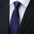 Detailed close-up of a classic navy blue men's business tie paired with a white dress shirt. - Navy Blue Glossy