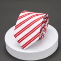 Close-up detail view of red and white striped men's necktie displayed on white podium. - H008