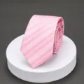 Detailed closeup of a pink patterned necktie featuring elegant geometric stripes and subtle diamond motifs. - Light Pink