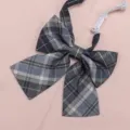 Close up view of the blue plaid JK uniform bowtie detail, featuring adjustable strap. - Blue-Grey Plaid