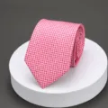 Detail view of a stylish pink patterned necktie neatly rolled on a white display podium. - Romantic Pink Dot