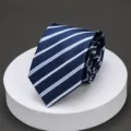 Close-up of a dark blue necktie with light blue white diagonal stripes rolled neatly on white. - A07