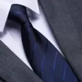 Close-up of mens classic navy blue striped tie with white dress shirt and grey suit jacket. - Blue Dark Stripe Zipper Style / 8cm
