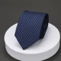 Detailed view of a classic blue business tie featuring a fine white patterned texture nicely folded. - LK Navy Silver Grid Dot