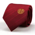 Close-up detail of a red men wedding necktie featuring gold embroidered double happiness motif. - Burgundy Striped Round Happiness Style