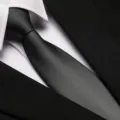 Close-up detail of a classic black business necktie featuring fine diagonal texture with shirt. - 8cm Gray Matte Plain Zipper