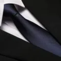 Detail view of a classic navy blue textured business necktie paired with white shirt and black suit. - 8cm Navy Small Grid Zipper