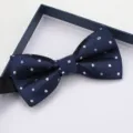 Primo piano dettaglio di un classico papillon a pois blu navy con confezione regalo. - Farfallino Brillante Blu