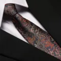 Detailed view of luxury paisley silk necktie with intricate orange and black floral patterns. - 8cm Auspicious Cloud Phoenix Zipper