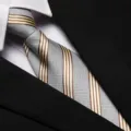 Close up view of a stylish grey and gold striped necktie worn with a formal suit shirt. - 8cm L027 Zipper