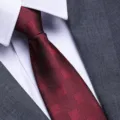 Detailed close-up of a stylish burgundy patterned mens formal tie paired with white shirt and suit. - 8cm Burgundy Block Zipper