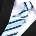 Closeup view of a stylish blue, white, and black striped necktie, ideal for business and formal wear. - Blue Stripe Zipper / 6 cm Wide / Blue