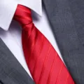 Close-up detail of a classic red striped mens tie paired with white shirt and suit jacket. - A023 Zipper