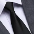 Dettaglio in primo piano di cravatta nera formale abbinata a camicia bianca e abito. - 8cm Nero Meteora Cerniera
