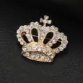 Primo piano dettagliato di una spilla a corona dorata intarsiata di strass trasparenti. - Spilla a Corona / Scatola regalo / Oro