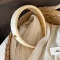 Detailed view of natural straw woven headband with elegant gold metal accent, premium texture. - Headband / Beige