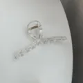 Transparent minimalist hair claw clip detail shot, showing clear resin texture and spring. - Clear
