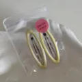 Detailed close-up of light yellow pearl hair clips in a clear bag on a white tray. - Oval Hollow BB Clip / 2 Pieces (6.6cm) / Yellow