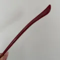 Acetate hair stick detail close-up, burgundy hair accessory texture and French handmade stamp. - Elegant Red