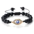 Elégant bracelet de perles noires avec pendentif œil doré en strass et cordon réglable. - Pierre Noire Veine Blanche Or