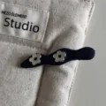 Close-up of a dark blue fabric hair clip with cute silver flower decorations on a canvas. - Wavy Bobby Pin / Denim Blue