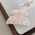 Detailed view of the pink acetate hair claw clip featuring sparkling rhinestones and metal studs. - Pink White