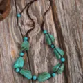 Close-up detail of the vintage ethnic handmade irregular turquoise bead necklace on rustic wood. - Irregular Turquoise Pendant Style (C23-572)
