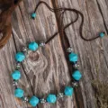 Detail view of ethnic turquoise beaded necklace with silver metal spacers and brown cord. - Faux Turquoise Square Bead with Metal Patterned Spacer Style (C23-573)