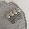 Detailed view of sweet iridescent heart hair comb with metal prongs for chic hairstyles. - White