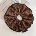 Detailed shot of large leopard print fabric scrunchie with black edge trim hair accessory style. - Hair Tie / Dark Leopard Print