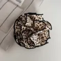 Nahaufnahme im Detail von dem stylischen Stoff Leopardenmuster Haargummi mit schwarzem Rand. - Knospen-Haarklammer / Helles Leopardenmuster