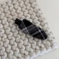 Gros plan détail de barrette à cheveux en tissu écossais noir et blanc sur fond tricoté. - Pinces à cheveux bec de canard / Pince Bec de Canard Plaid Noir