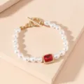 Close-up detail of vintage style pearl bracelet with gold toggle clasp and red gemstone charm. - Red Gem Bracelet (AMY735R)