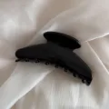 Black hair claw clip detail showing smooth glossy finish and sturdy teeth design for styling. - Black
