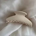 Close-up of elegant beige hair claw clip, minimalist design on soft white silk fabric. - Cream White