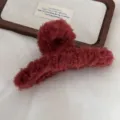 Detailed shot of dark red plush hair claw clip, soft fluffy winter hair accessory. - Red