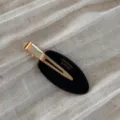 Close-up view of the elegant black and gold oval hair clip featuring a secure duckbill design. - Black